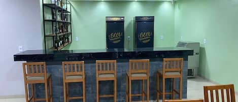 A bar area with a black countertop, wooden chairs, and two refrigerators with 'Beer' branding.