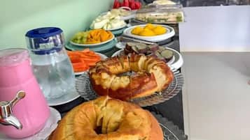 A buffet table with various food items and a pink drink.