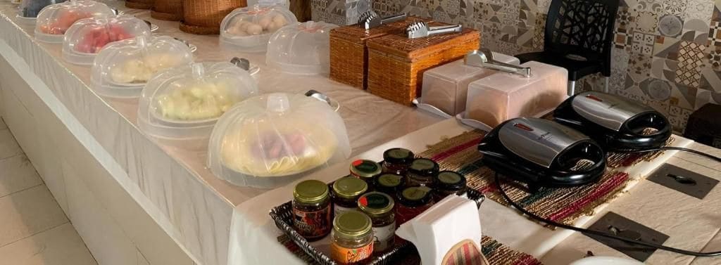 A buffet setup with covered food items, condiments, and a microwave.
