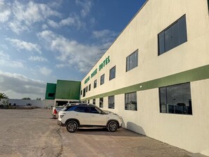 A hotel with a white facade and green accents, a parked SUV, and a clear sky. - Lençóis Prime Hotel (Barreirinhas)