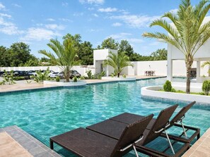 A swimming pool with lounge chairs, palm trees, and a white building in the background. - Lençóis Prime Hotel (Barreirinhas)