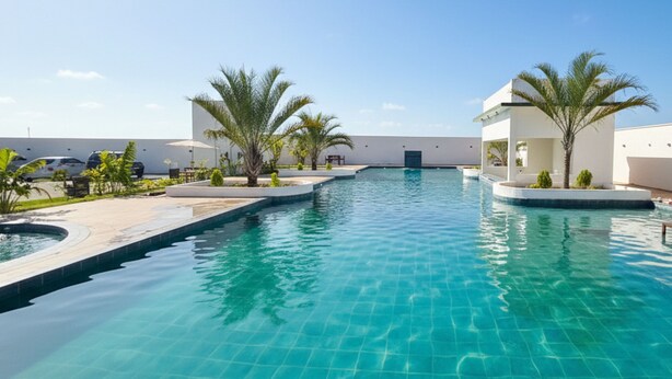 A swimming pool with clear blue water, surrounded by palm trees and modern buildings.