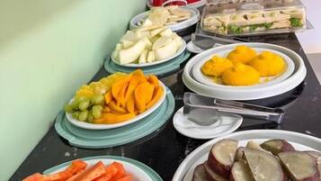 A buffet with various food items including sliced fruits, vegetables, and sandwiches.