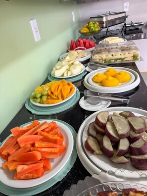A buffet with various food items including sliced fruits, vegetables, and sandwiches. - Lençóis Prime Hotel (Barreirinhas)