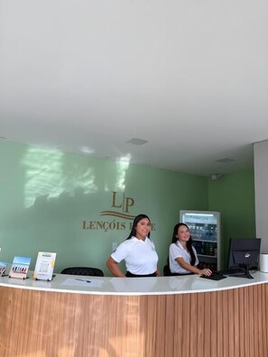 A reception desk with a green wall and a sign that reads 'LENCÔIS LOBOS'. - Lençóis Prime Hotel (Barreirinhas)