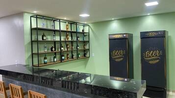 A bar area with a glass counter, shelves with bottles, and two refrigerators labeled 'Beer'.