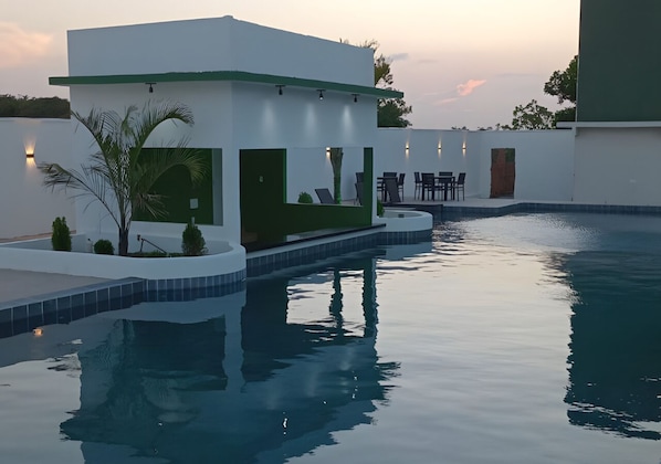 Una piscina al aire libre, sillones reclinables de piscina