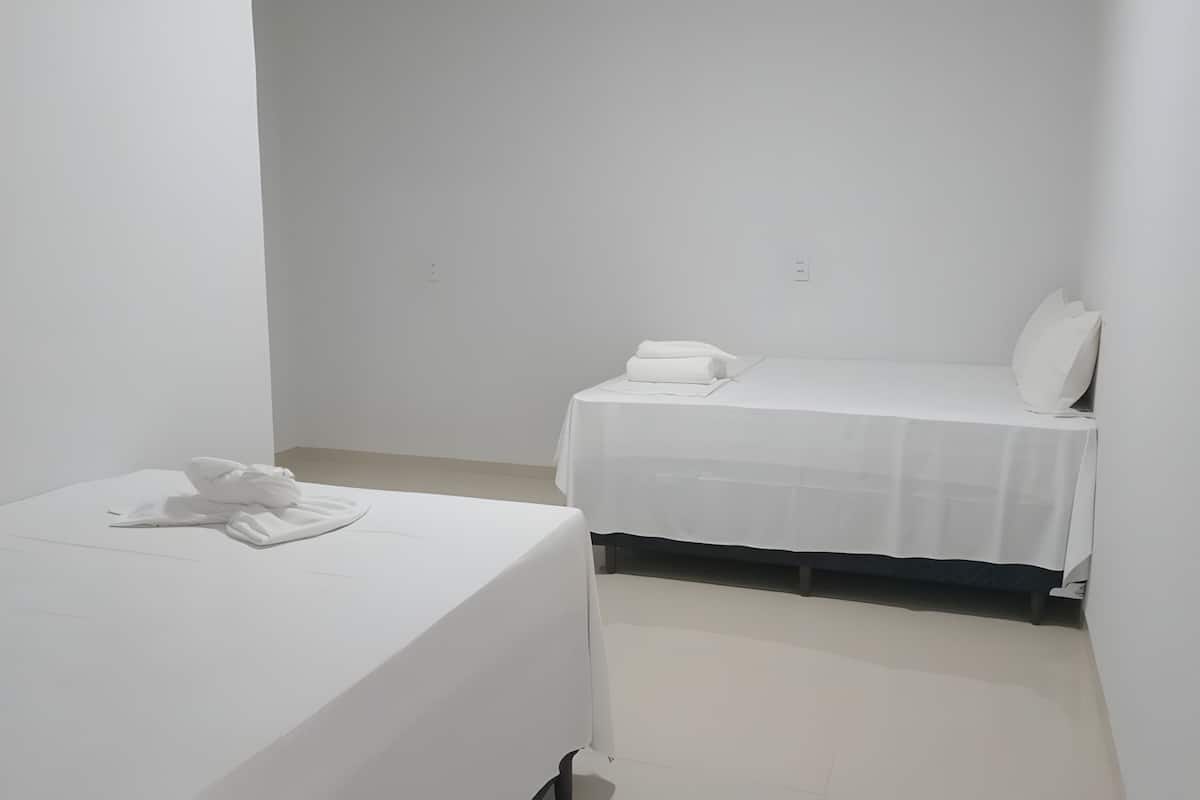 A small, clean room with a single bed, a bedside table, and a white wall.