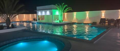 Una piscina al aire libre, sillones reclinables de piscina