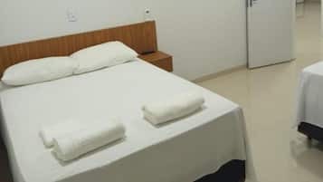 Una habitación de hotel con una cama, una mesita de noche y un refrigerador.