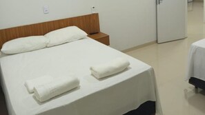 Ein Hotelzimmer mit Bett, Nachttisch und Kühlschrank.