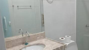 A bathroom with a sink, mirror, toilet, and towel ring.