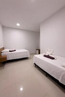Una habitación de hotel con dos camas, una mesita de noche y un armario pequeño.