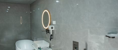 A modern bathroom with a freestanding bathtub, a vanity with a mirror, and a handheld showerhead.