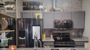 A modern kitchen with grey cabinets, stainless steel appliances, and a marble countertop.