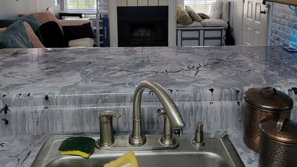 A kitchen with a marble countertop, a sink with modern faucets, and a fireplace.