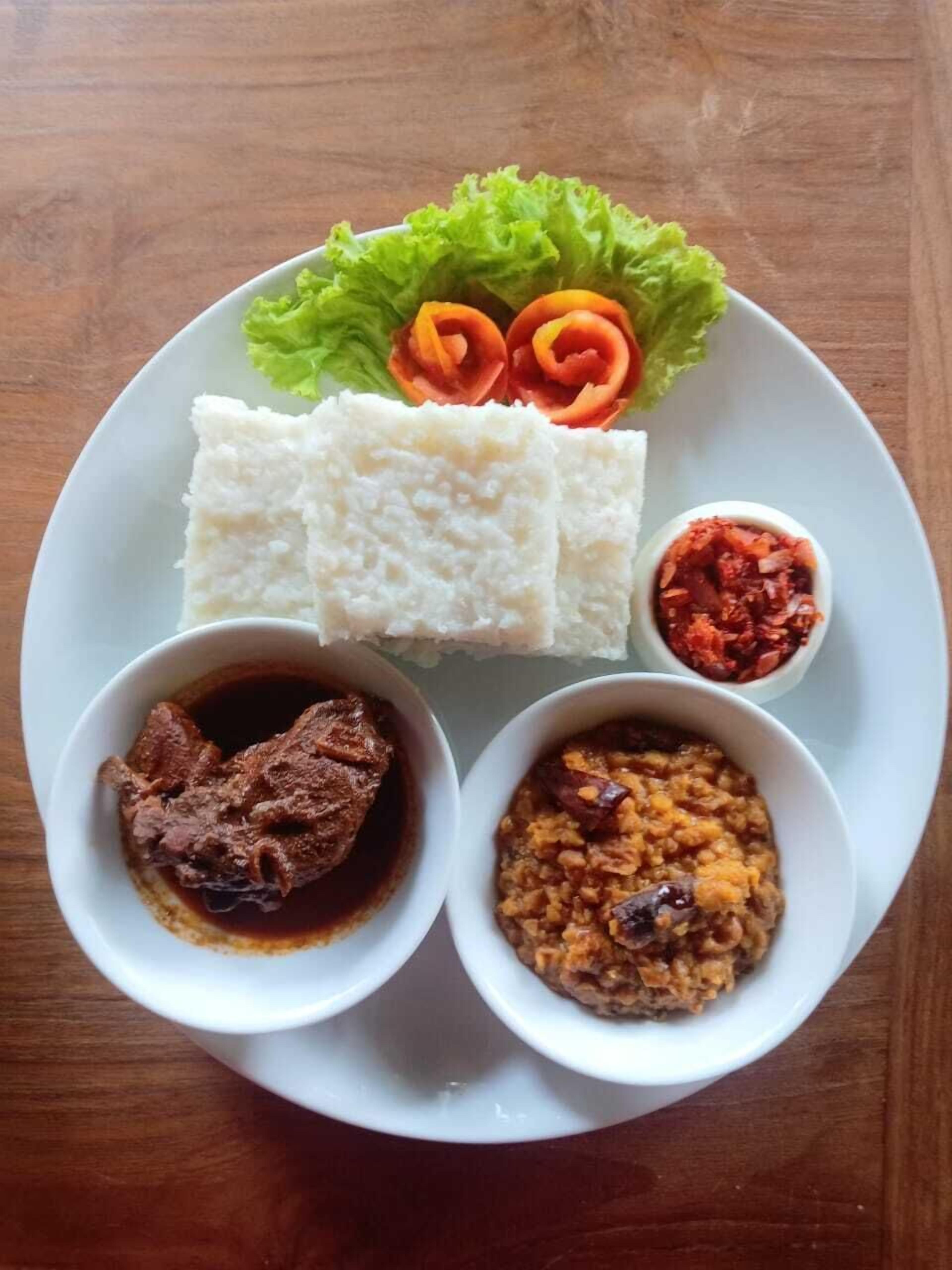 A plate with white rice, a small bowl of red sauce, a bowl of dark brown sauce, a bowl of yellowish dish, and a piece of meat.