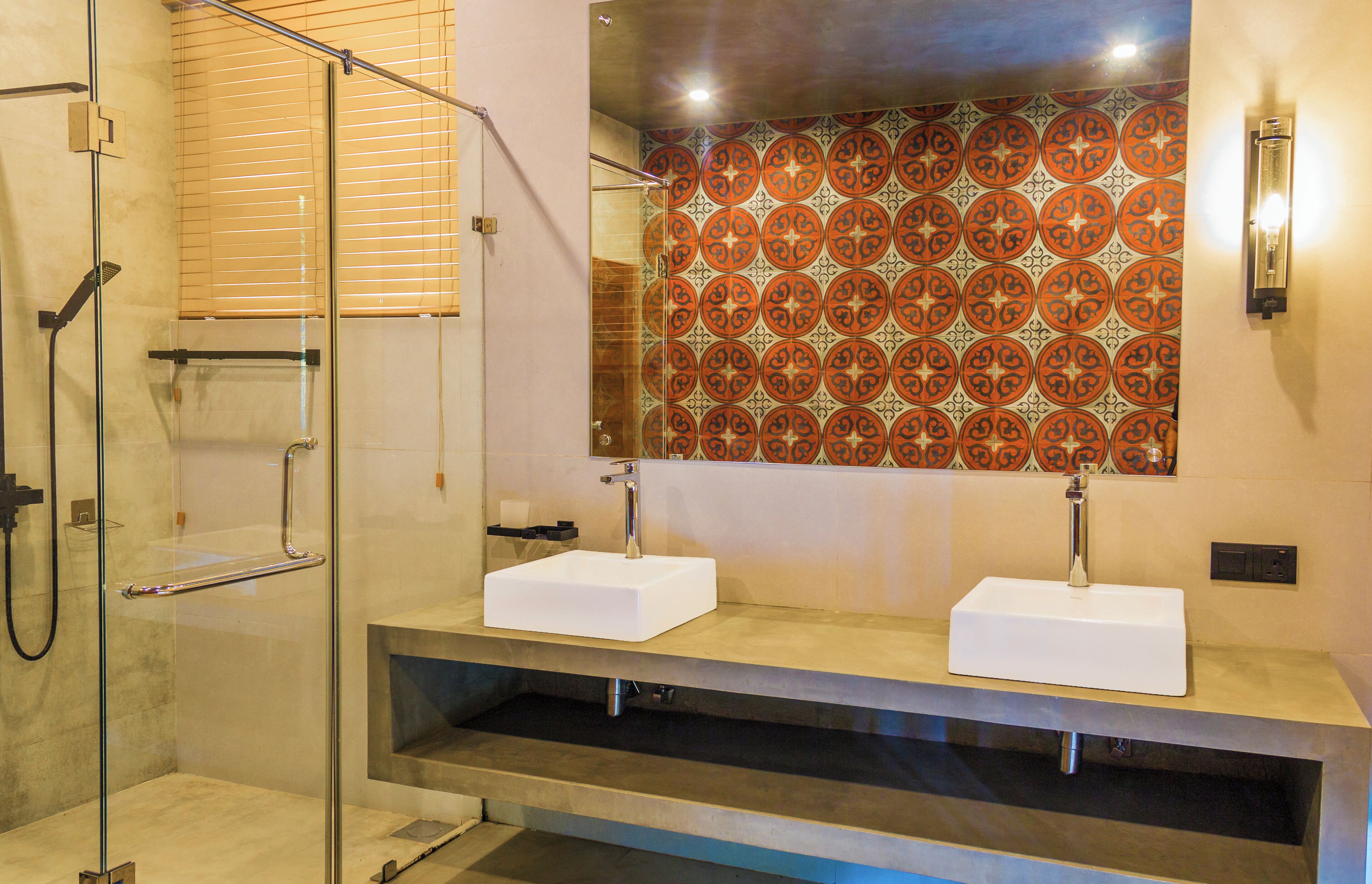 A modern bathroom with a glass-enclosed shower, two sinks, and a decorative tile backsplash.
