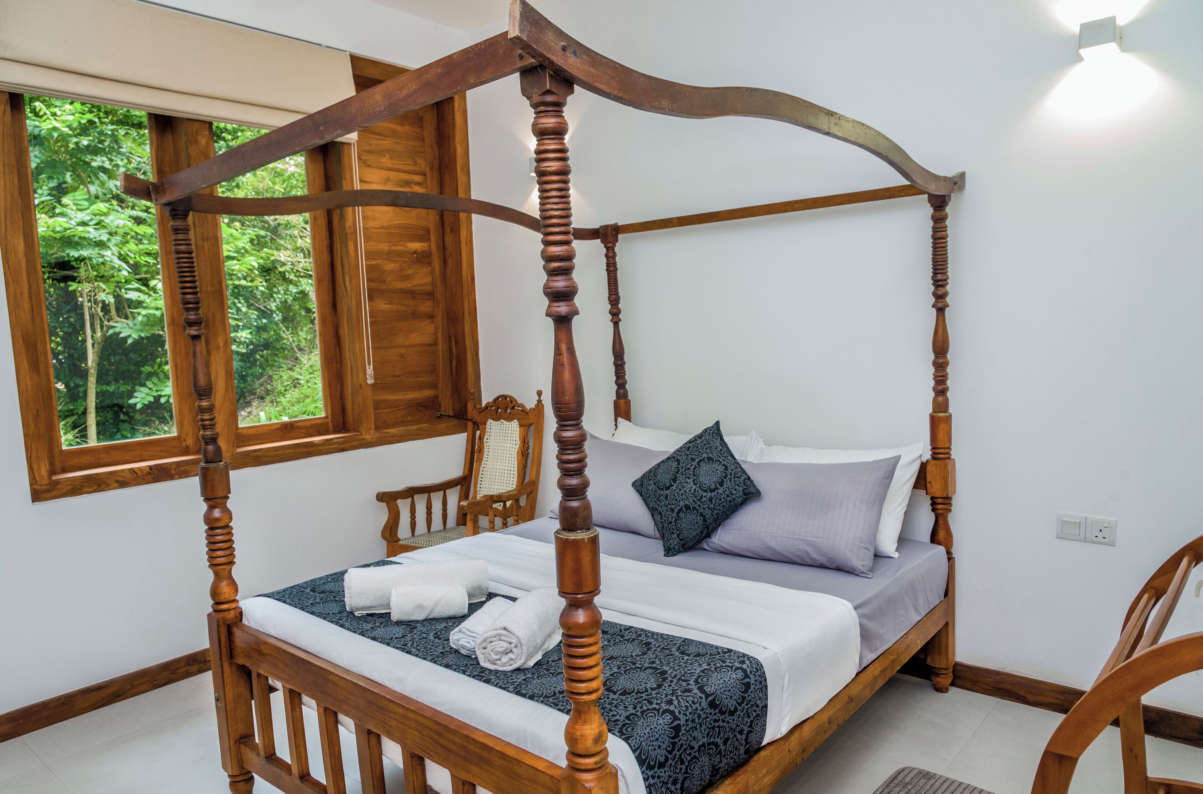 Un lit à baldaquin avec un cadre en bois, une couvre-lit à motifs sombres et un oreiller à motifs géométriques.