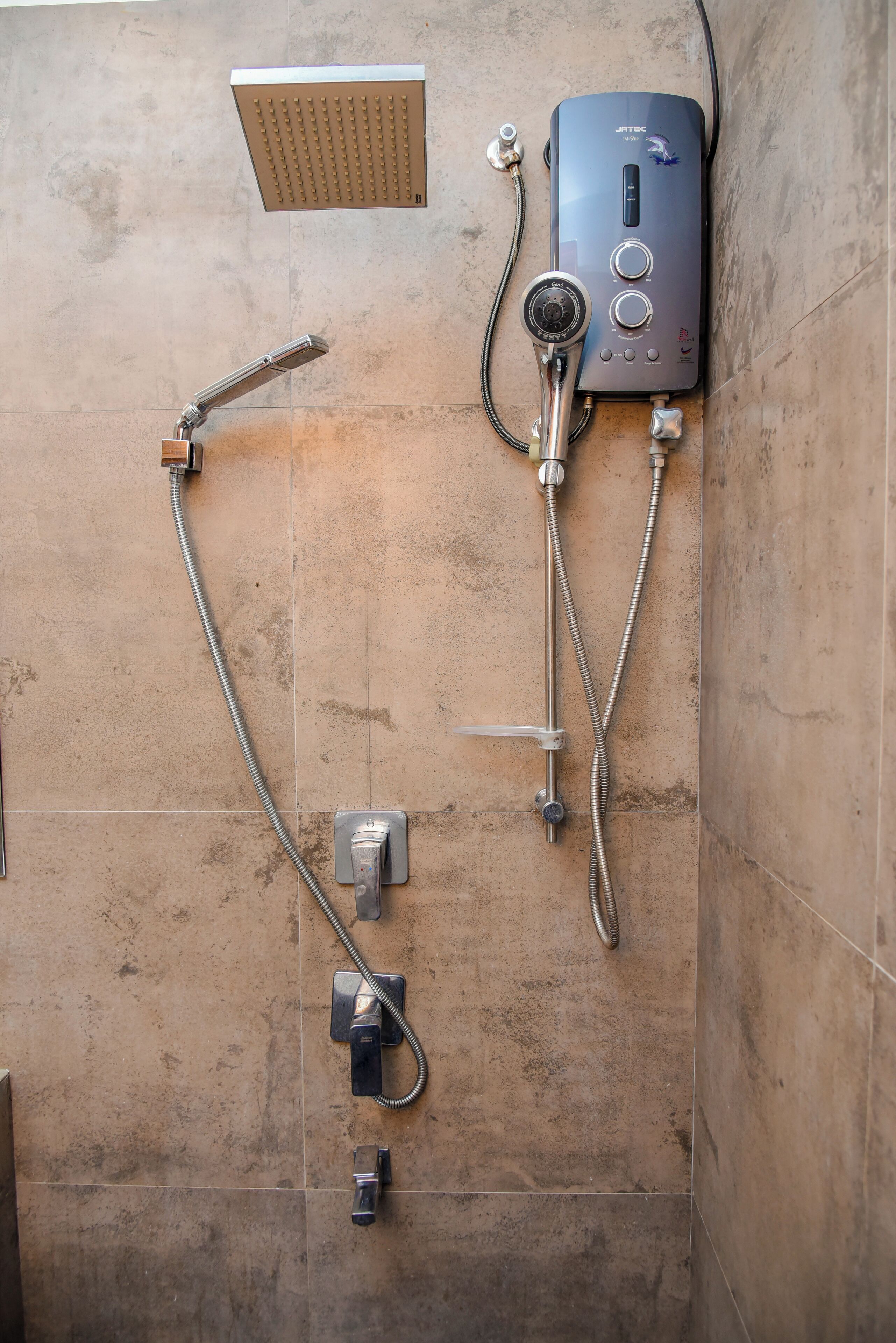 A shower area with a wall-mounted control panel, a handheld showerhead, and a fixed showerhead.