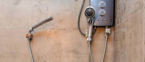 A shower area with a wall-mounted control panel, a handheld showerhead, and a fixed showerhead.