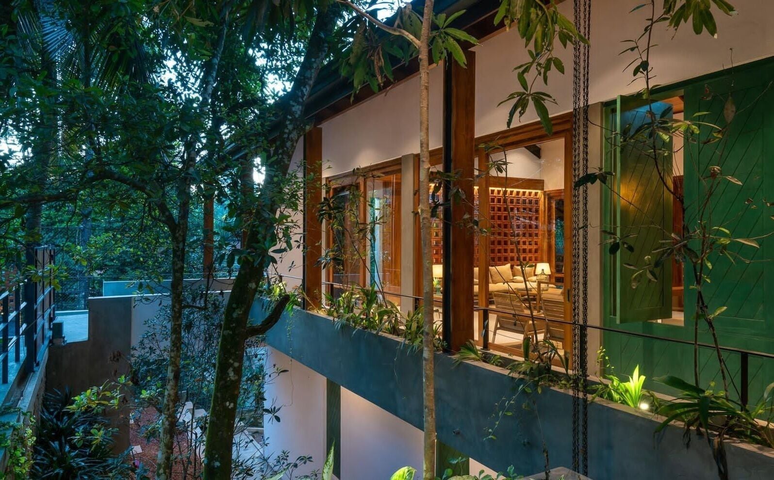 A modern building with a balcony overlooking a lush garden.