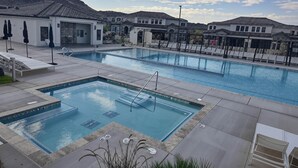 Zona de piscina con varias piscinas, sillas de descanso y sombrillas.