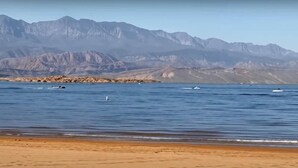 Una playa con una cadena montañosa al fondo.