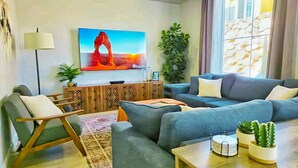 Una sala de estar moderna con un sofá gris, una mesita de madera y un televisor montado en la pared.