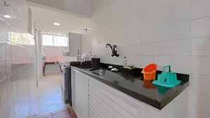 Una cocina moderna con armarios blancos, encimera negra y un lavamanos. Hay dos botes pequeños sobre la encimera.