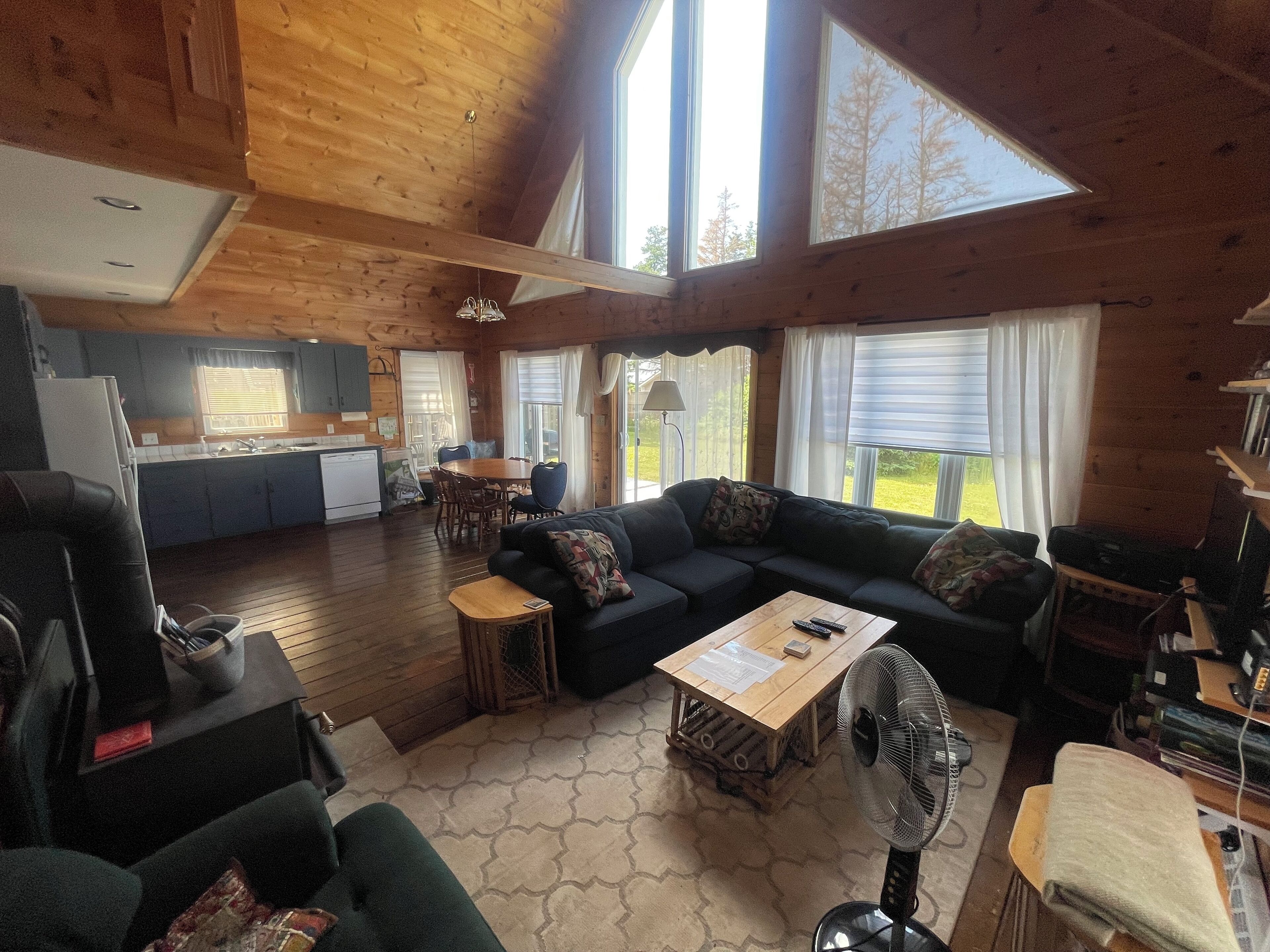 En rummelig hytte med træpaneler, et spiseområde og en opholdsstue med sofa og sofabord.