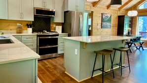 Een moderne keuken met houten balken, een centraal eiland, barstoelen en uitzicht op de omgeving.