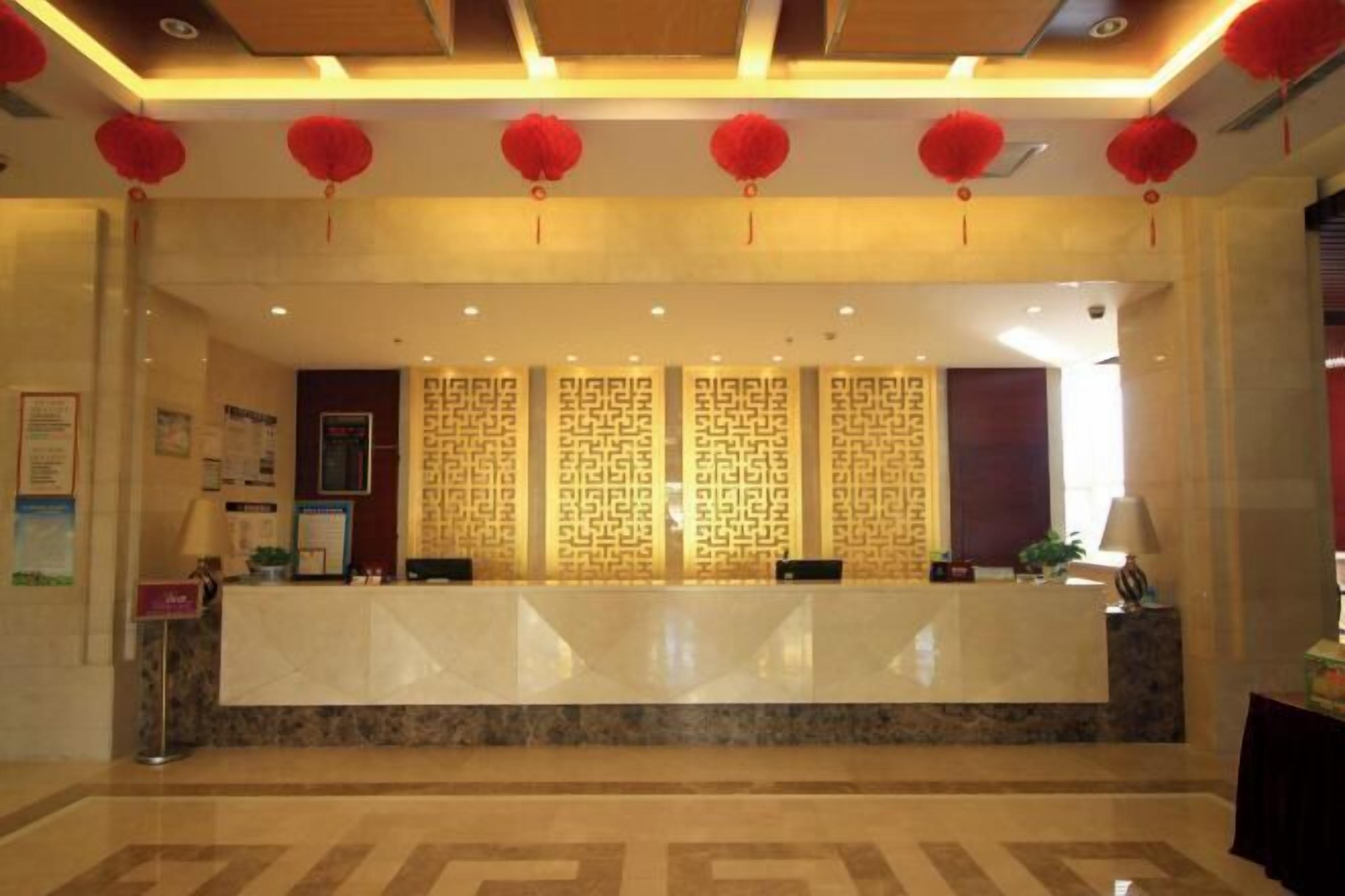 Zona de recepción de hotel con mostrador de mármol, faroles rojos y paneles decorativos.