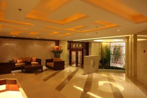 A hotel lobby with a reception desk, seating area, and a large plant. - Qilu Wangfu Hotel (Laiyang)