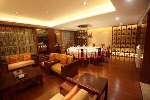 A spacious living area with a dining table, sofas, and a shoe display wall. - Qilu Wangfu Hotel (Laiyang)