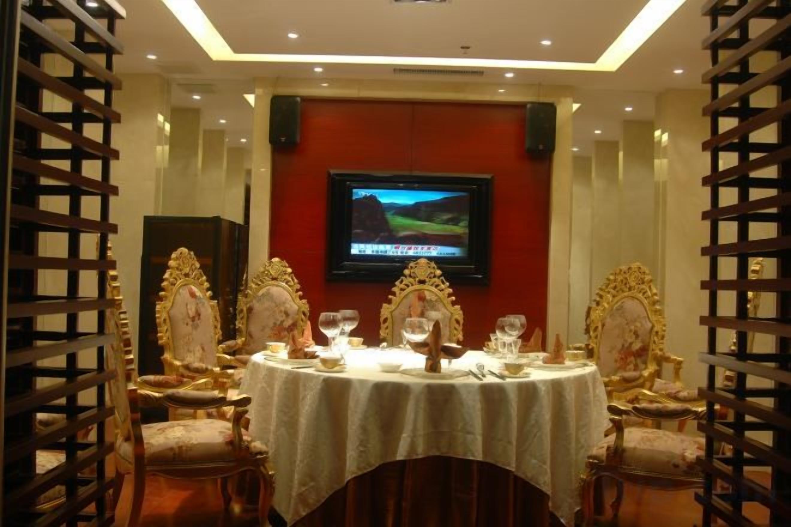 Un comedor con una pantalla de televisión, sillas ornamentadas y una mesa preparada para una comida.