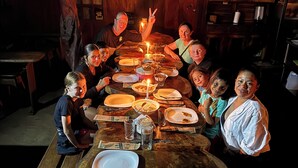 A group of people seated around a wooden dining table with plates, glasses, and a candle. - Nestled at the base of Rincon de la Vieja Volcano and bordering the Rio Celeste. (Buenas Aires)