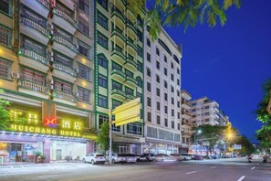 A hotel with multiple floors, a prominent sign, and a street view with parked cars. - Dongxing Huichang Fashion Hotel (Dongxing)