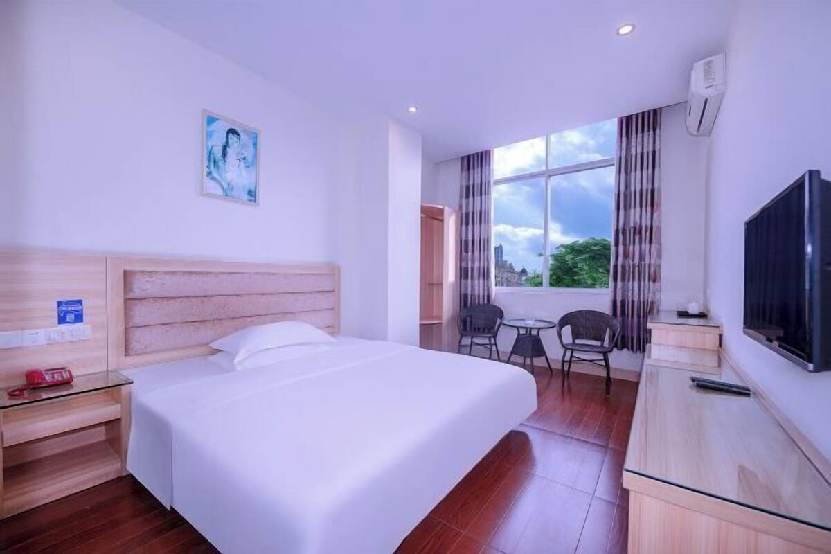 Ein Hotelzimmer mit Bett, Schreibtisch, Stuhl, Fernseher und einem Fenster mit Blick.