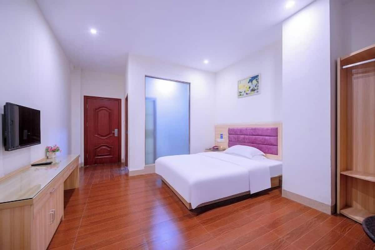 Ein Hotelzimmer mit einem Bett, einem Fernseher, einem Schreibtisch und einer Tür.