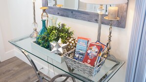 A glass-top table with decorative items, including a star-shaped object, a blue vase, and a basket containing books and a candle.