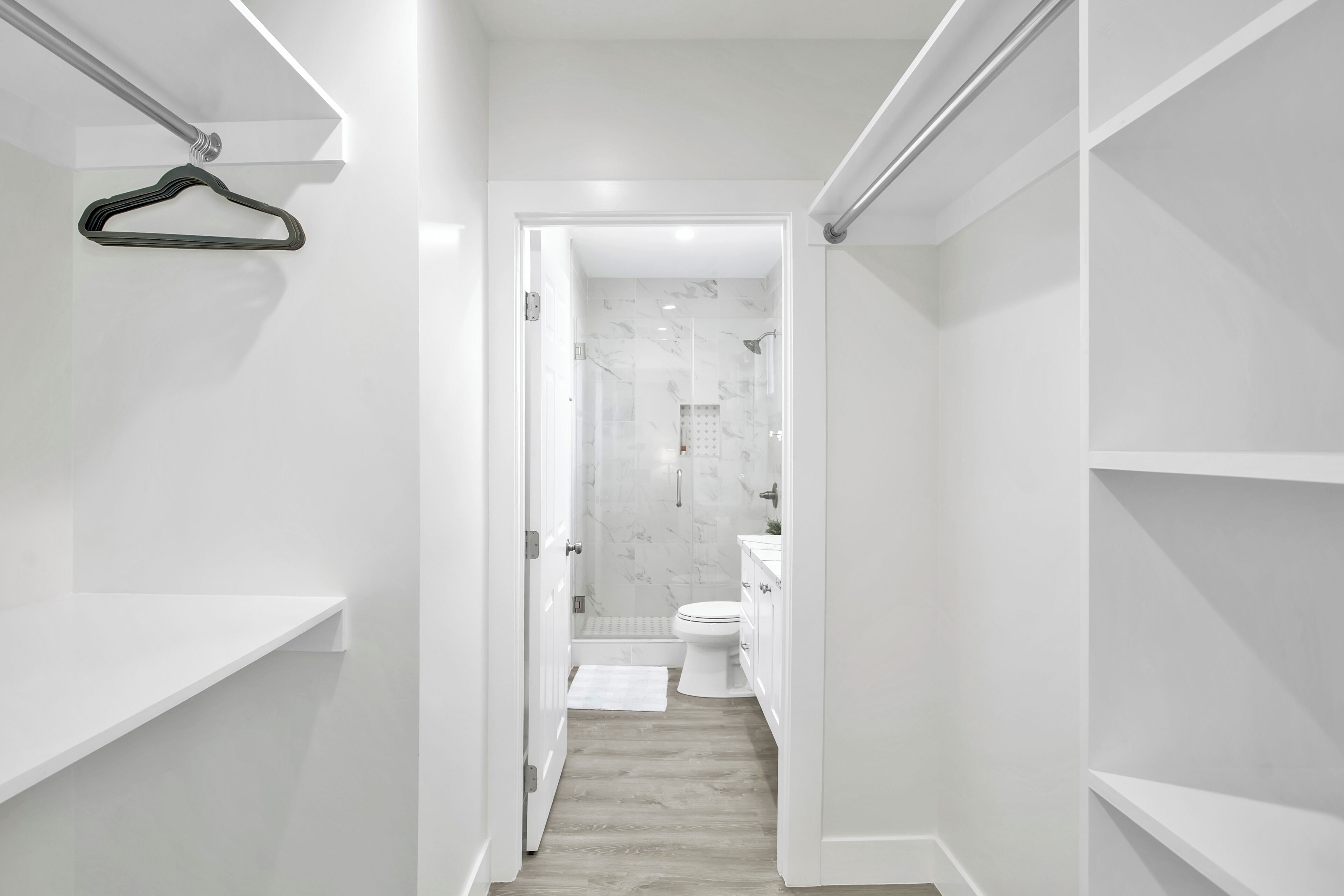 Un pasillo estrecho que conduce a un baño con inodoro, ducha y paredes de mármol.