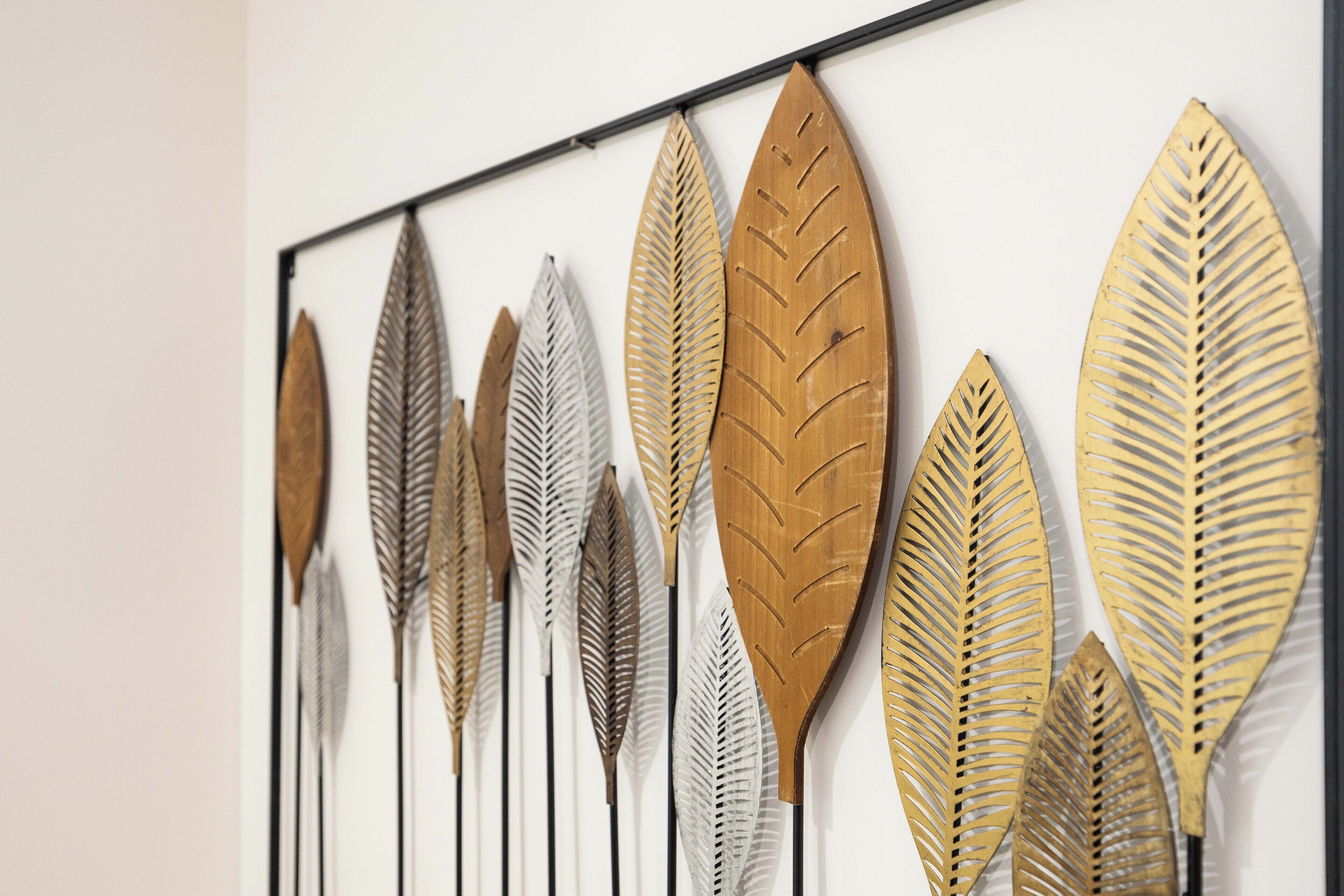 A wall with a series of decorative leaf-shaped metal pieces.