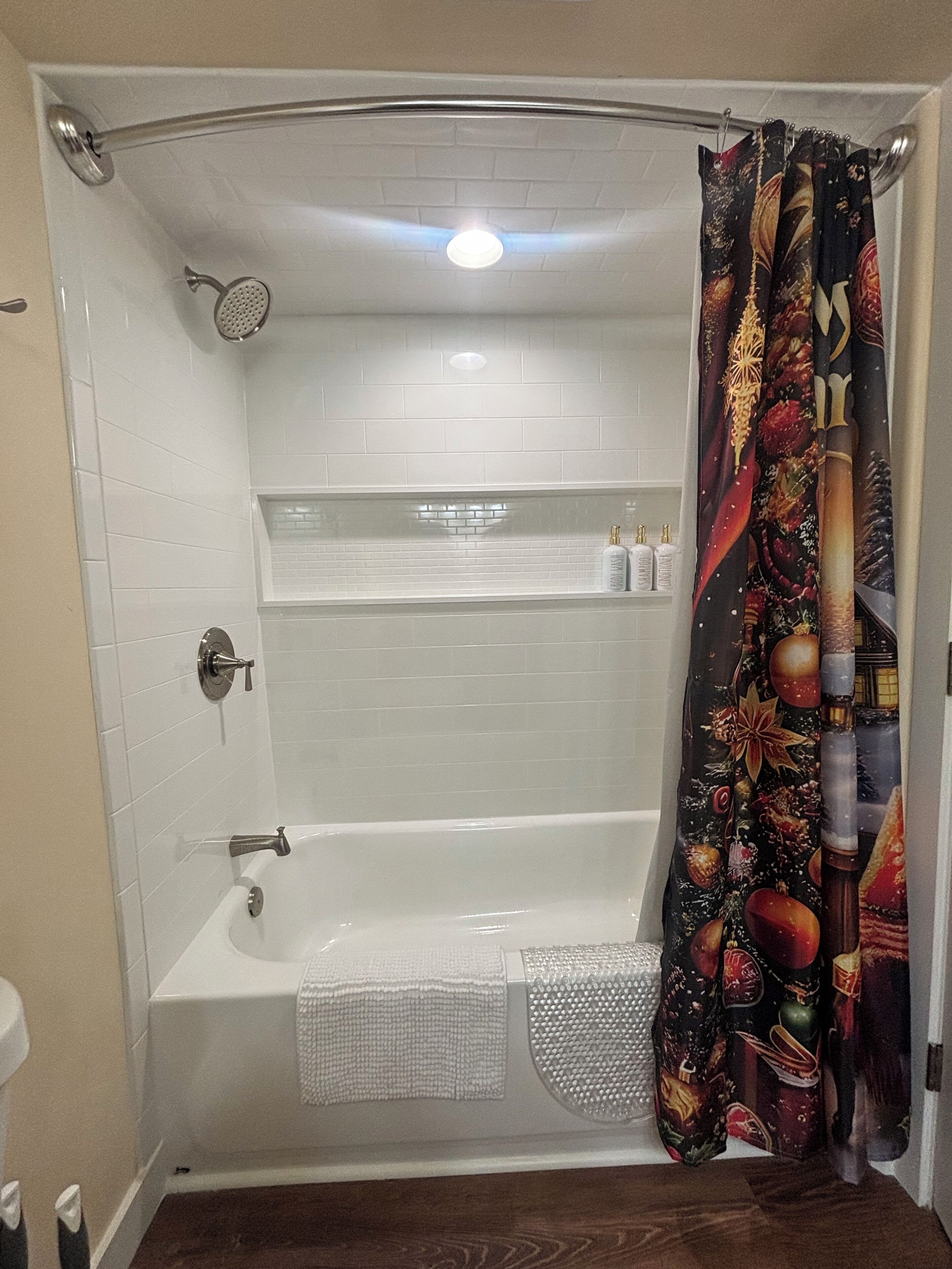 Un bagno moderno con una vasca da bagno bianca, un soffione e una tenda da doccia decorativa.