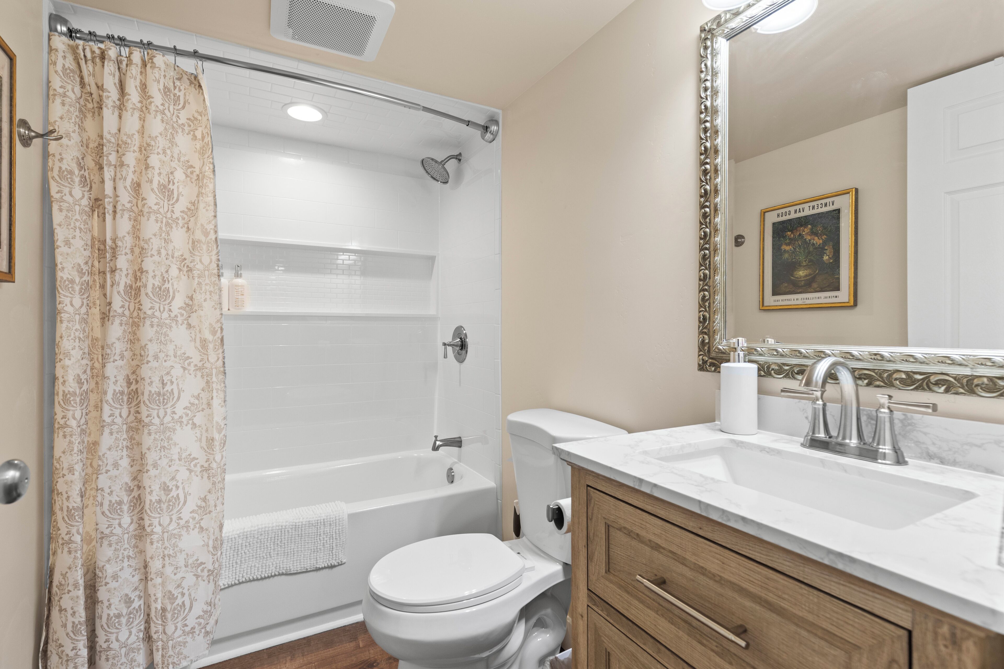 A bathroom with a shower, toilet, sink, and vanity.
