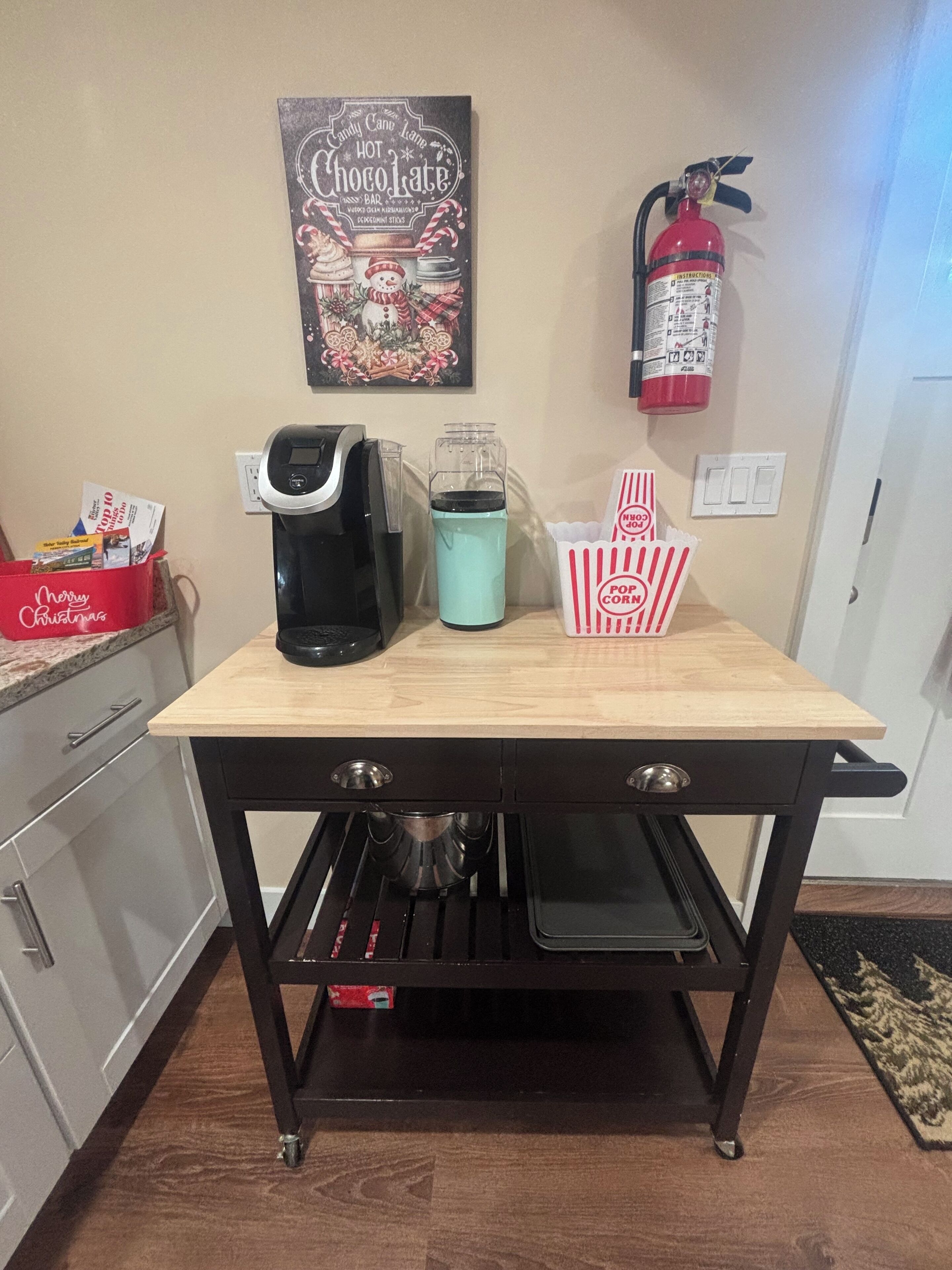 A kitchen counter with a coffee maker, a kettle, and a popcorn container.