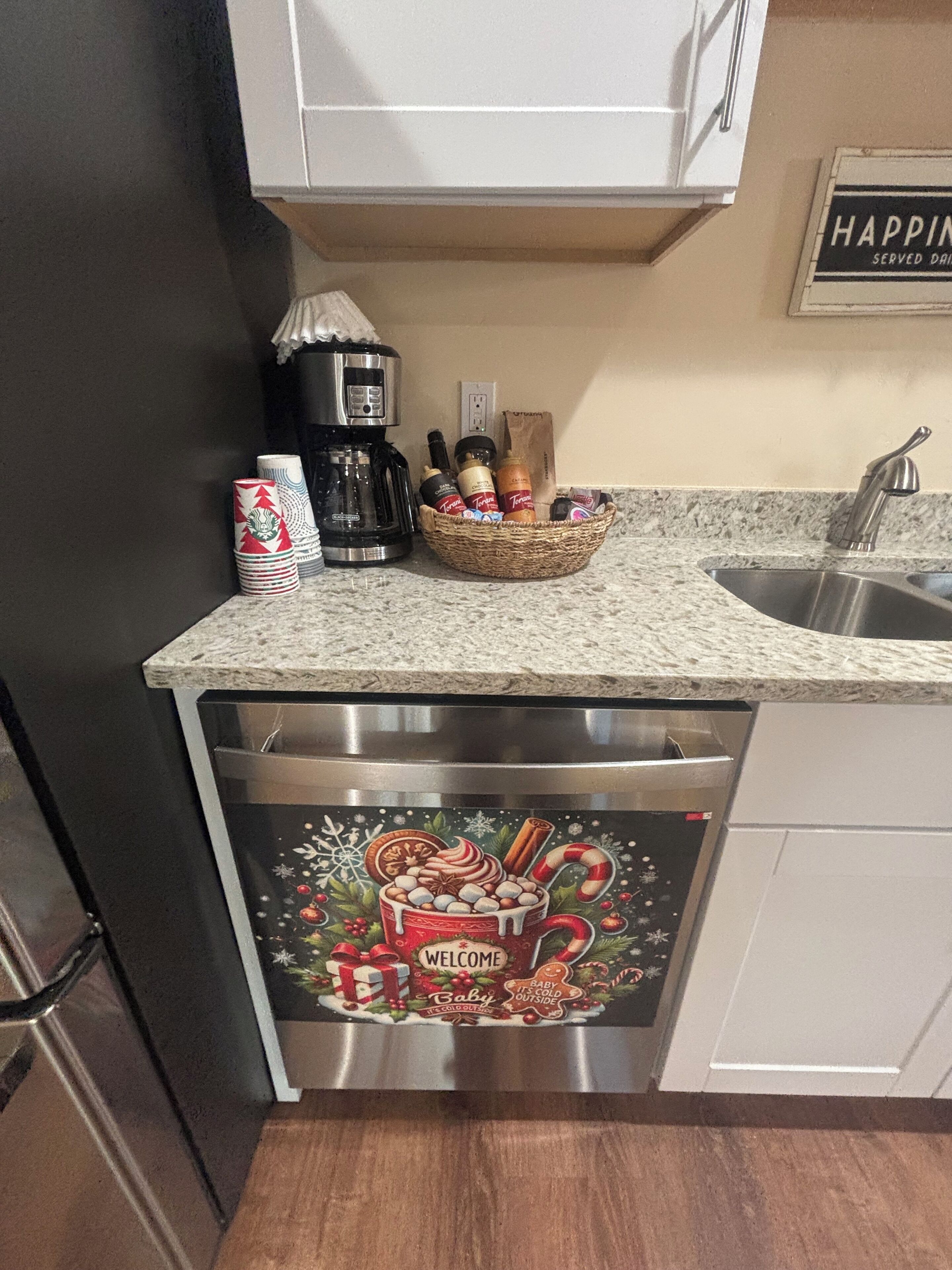 Ett kök med en kaffebryggare, en korg med snacks och en diskmaskin med en festlig design.