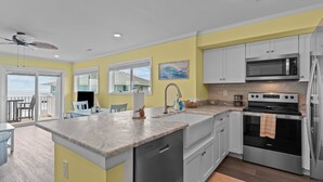 A modern kitchen with white cabinets, a stainless steel microwave, and an oven. - Shorething- oceanfront-pool View-third floor condo -sleeps 6 (Kure Beach)