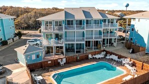 A multi-story hotel with a pool area, outdoor seating, and a view of the surrounding landscape. - Shorething- oceanfront-pool View-third floor condo -sleeps 6 (Kure Beach)