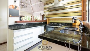 A kitchen with a stove, sink, and a backsplash with yellow and white tiles.